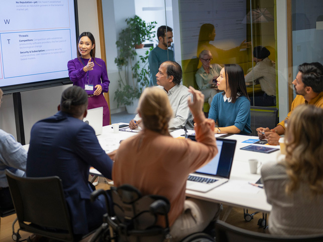 Female asian leader engaging a diverse team during a presentation and meeting